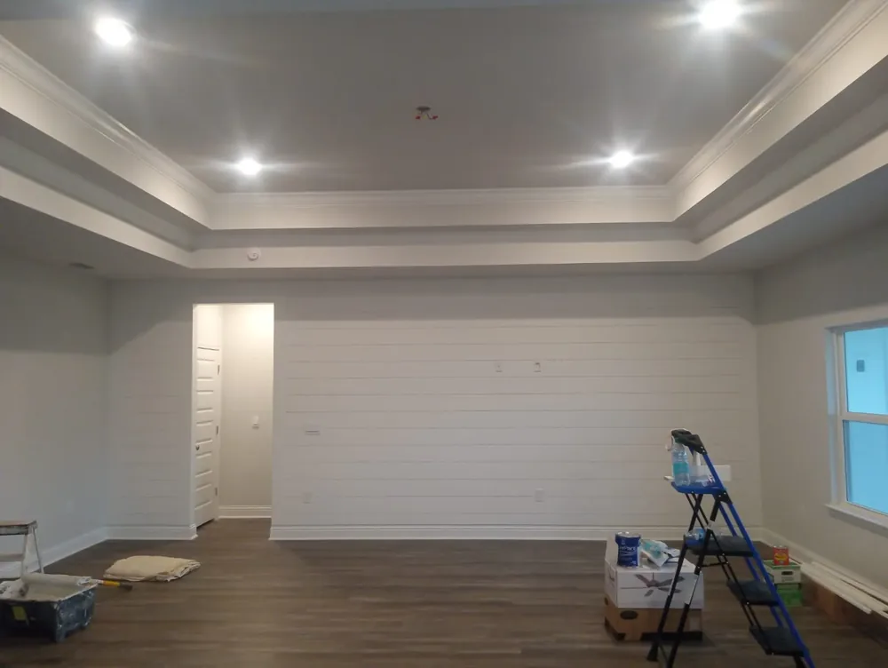 Freshly painted living room with tray ceiling, crown molding, and white shiplap accent wall