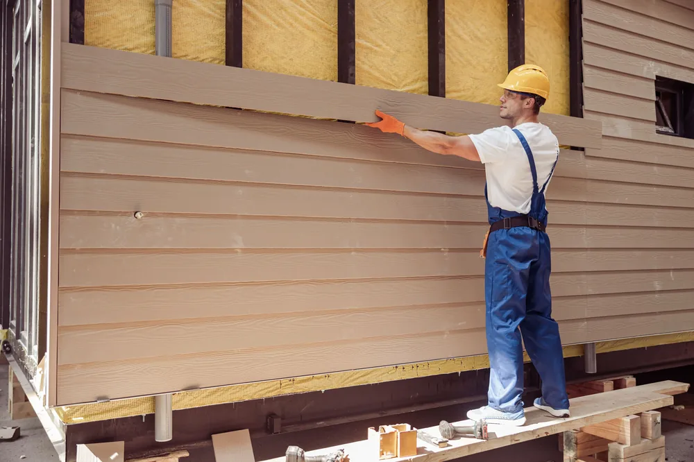 Installer fitting new fiber cement siding panels on a home